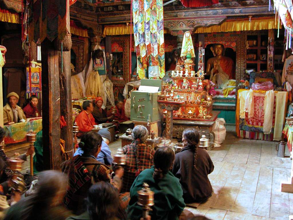 Annapurna 12 11 Braga Gompa Inside The main temple is dark, mysterious and powerfully atmospheric. The people were spinning their prayer wheels and chanting Om Mani Padme Hum three times with each breath. The altar is the usual jumble of butter lamps, vases of plastic flowers, masks, tinsel and photos of the Dalai Lama.